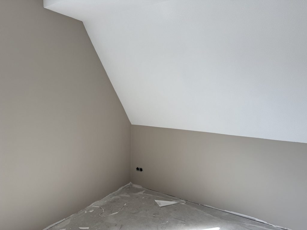 Zolderkamer met een schuine wand, afgewerkt in een zachte beige tint